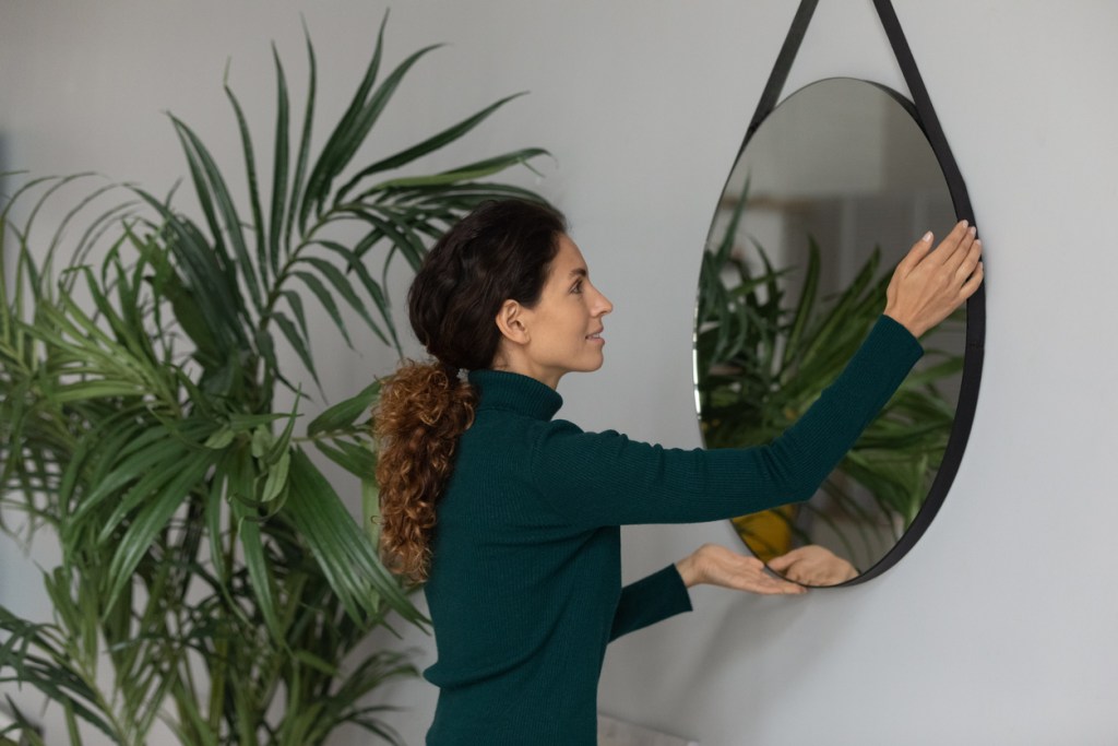 Mujer colocando un espejo. Casa en orden - Imagen: iStock
